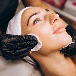 Cosmetologist cleaning face of a woman in a beauty salon